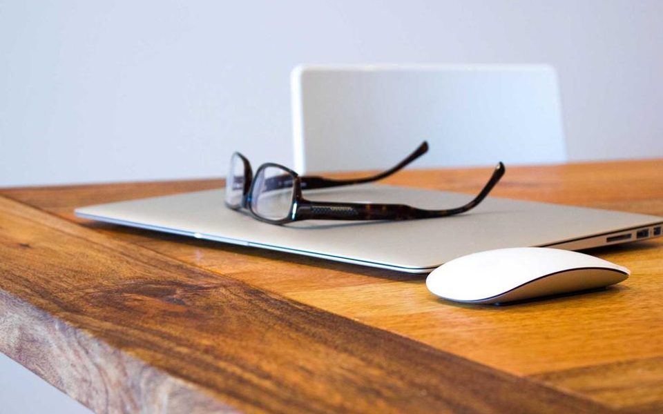 A notepad with handwritten notes beside a pair of glasses